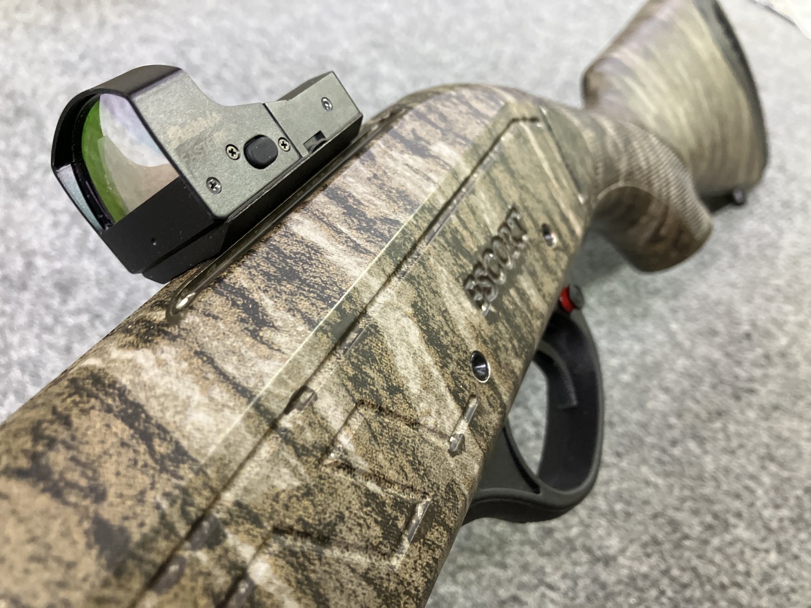 Camouflage-matched red dot optic mounted on an Escort shotgun